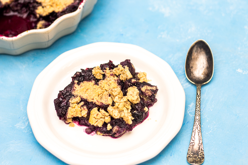 Vegan Gluten-free blueberry cobbler on a plate with the pie plate in the background