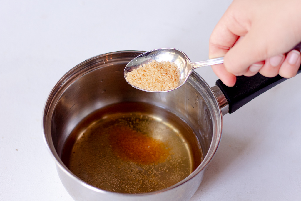 Someone adding sugar to a saucer pan with water