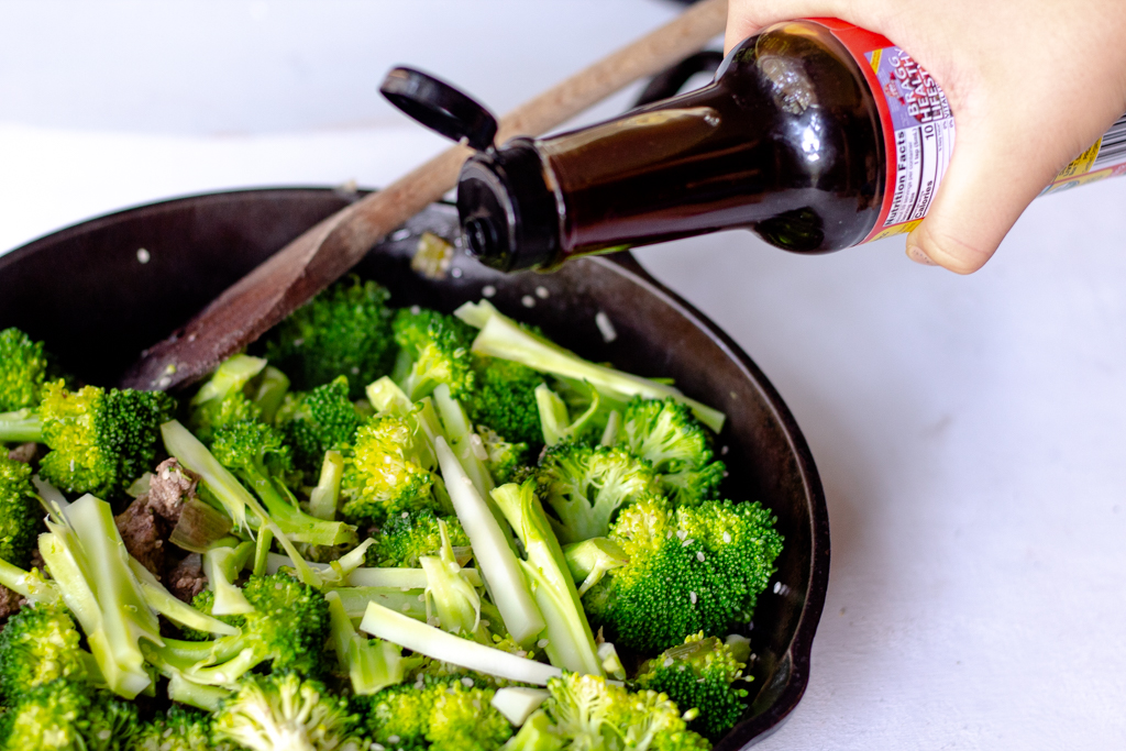 Someone adding Coconut aminos to the skillet